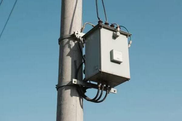 Utility worker performing maintenance on a pole transformer
